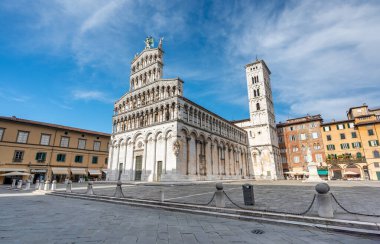 Lucca İtalya 'nın tarihi merkezinde, Chiesa di San Michele' in panoramik manzarası güneşli bir yaz gününde açık mavi gökyüzü ve antik mimaride sıcak bir ışık
