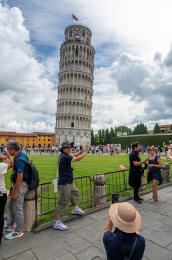 Pisa, İtalya - 12.6.2024: Eğik Pisa Kulesi önünde poz veren turistler (Torre Pendente di Pisa), simgesel eğimli yapıyı destekliyormuş gibi görünmek için zorla perspektif kullanıyorlar.