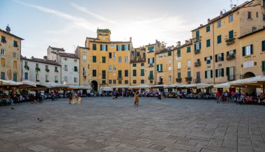 Lucca, İtalya - 12.6.2024: Bir zamanlar Roma amfitiyatrosu olan Lucca, İtalya 'daki Piazza dell Anfiteatro, şimdi kafeler, restoranlar ve canlı atmosferin keyfini çıkaran turistlerle dolu canlı bir oval meydan.