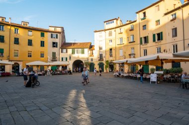 Lucca, İtalya - 12.6.2024: Bir zamanlar Roma amfitiyatrosu olan Lucca, İtalya 'daki Piazza dell Anfiteatro, şimdi kafeler, restoranlar ve canlı atmosferin keyfini çıkaran turistlerle dolu canlı bir oval meydan.
