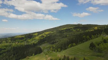 Yamaç paraşütçüleri ve planörlerin havada süzüldüğü ikonik kulesiyle Jested Dağı 'nın etrafındaki orman ve çayır görüntüleri..