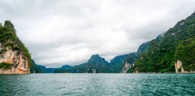 Tayland 'ın Krabi ilindeki Khao Sok Gölü manzarası. Yüksek kireçtaşı uçurumları, gölün sakin yüzeyinden yükselen tropikal yağmur ormanlarıyla kaplı..