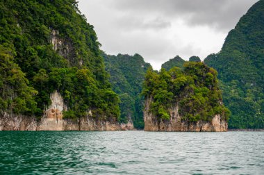 Tayland 'ın Krabi ilindeki Khao Sok Gölü manzarası. Yüksek kireçtaşı uçurumları, gölün sakin yüzeyinden yükselen tropikal yağmur ormanlarıyla kaplı..