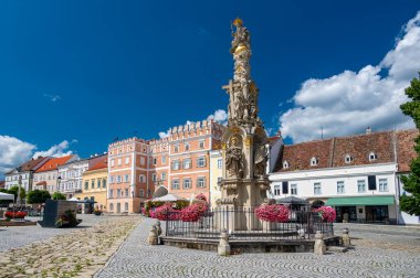 Avusturya, Retz 'deki ana meydanın panoramik manzarası, Kutsal Üçlü Sütun, renkli binalar, belediye kulesi, çiçek açan çiçekler ve sıcak yaz atmosferi.