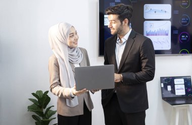 Genç bir yönetici ve bir bayan çalışan dizüstü bilgisayara bakıyor. Şirketin online iş toplantıları için.