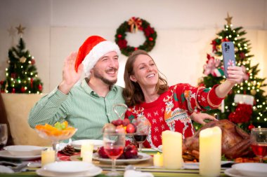 Genç bir çift evdeki Noel partisinde selfie çekiyor.