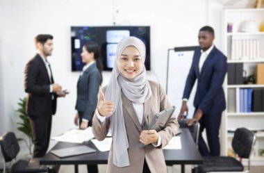 Genç Müslüman bir işkadını ofis ortamında bir tablet tutuyor..