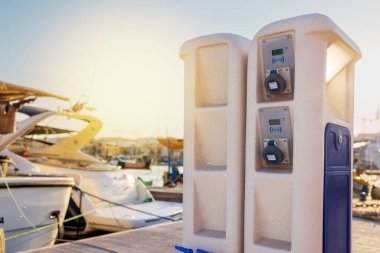 Deniz kıyısındaki iskelede elektrik prizleri. Akdeniz 'deki tekneler için şarj istasyonu. Limandaki gemileri şarj etmek için elektrik prizleri. Akdeniz, deniz, yat parkı.