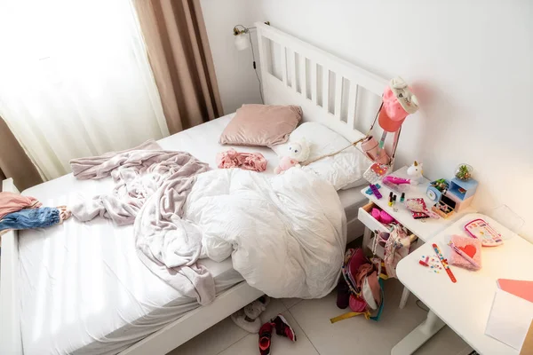 Mess in the little girls room. close-up of a white bed and nightstand where things are in a mess. everything is pink. The concept of raising a child, accustoming to order.
