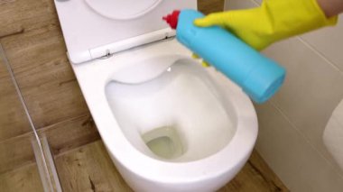 Sarı koruyucu eldivenler giymiş, sifonu, dezenfeksiyonu ve hijyen konseptini temizlemek için mavi şişedeki sıvı temizleme solüsyonunu kullanan kadınların yakın çekimleri. ev temizliği, oda hijyeni.