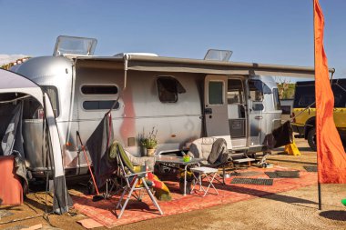 Vintage Airstream karavanı bir kamp alanına park edilmiş. Dışarısı seyahat ve emeklilik özgürlüğünü sembolize ediyor..