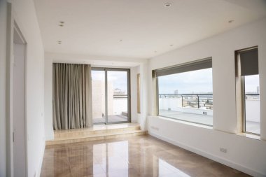Büyük pencereli, perdeli, kapılı, mermer zeminli ve gün ışığında modern boş bir oda..