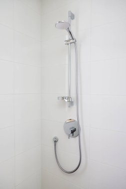 Temiz modern krom duş başlığı ve kontrol paneli banyonun içindeki beyaz fayans duvarında..