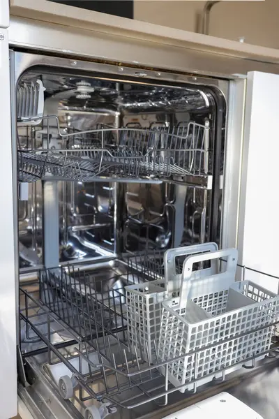 Boş rafları ve sepeti olan açık ve temiz bulaşık makinesi, metal ve plastik parçalarla iç görünümü.