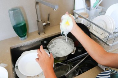 Mutfak lavabosunda sabun ve süngerle bulaşık yıkayan kişiye yakın çekim, günlük ev işleri.