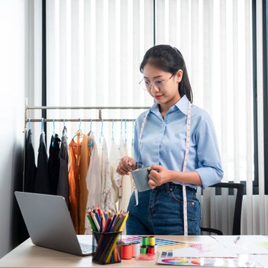 Profesyonel kadın moda tasarımcısı çalışıyor ve düşünüyor. Yeni kıyafet koleksiyonu malzemesi ve renk örneği seçmeye karar veriyor..