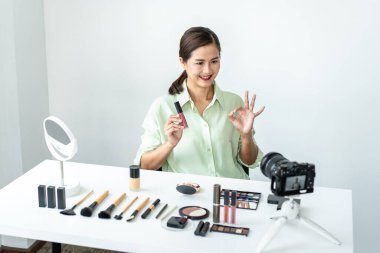 Kadın blogcu, makyaj malzemesi kozmetik inceleme ürünü ve canlı yayın videosunu kamera ekranında sosyal ağ öğretimine gösteriyor..