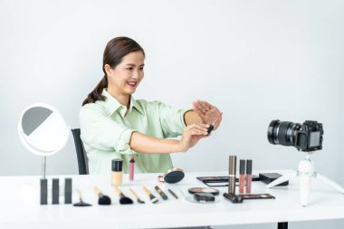 Kadın blogcu, makyaj malzemesi kozmetik inceleme ürünü ve canlı yayın videosunu kamera ekranında sosyal ağ öğretimine gösteriyor..