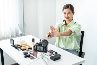 Kadın blogcu, makyaj malzemesi kozmetik inceleme ürünü ve canlı yayın videosunu ofis stüdyosundaki kamera ekranında öğretmenliğe sunuyor..