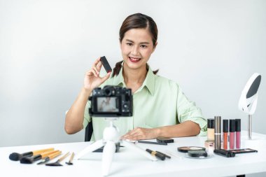 Kadın blogcu, makyaj malzemesi kozmetik inceleme ürünü ve canlı yayın videosunu ofis stüdyosundaki kamera ekranında öğretmenliğe sunuyor..