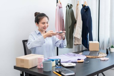 Moda tasarımcısı kadın ürünleri satar ve müşteriden sipariş alır ve müşteriye eve teslimat için kıyafet paketlerini kutulara doldurur..