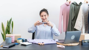 Moda tasarımcısı kadın ürünleri satar ve müşteriden sipariş alır ve müşteriye eve teslimat için kıyafet paketlerini kutulara doldurur..