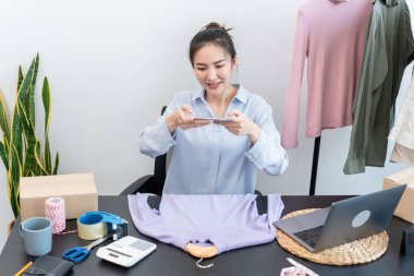 Moda tasarımcısı kadın ürünleri satar ve müşteriden sipariş alır ve müşteriye eve teslimat için kıyafet paketlerini kutulara doldurur..