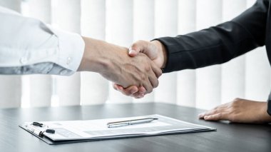 Erkek işveren, başarılı bir iş görüşmesinden sonra yeni çalışanı tebrik etmek ve ofisteki toplantı odasında sözleşmeyi imzalamak için el sıkışıyor..