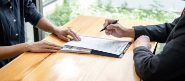 Rüşvet veren işadamına bir kalem veriyor ve iş adamına arazi ve gayrimenkul satın almada yolsuzluk yaparken sözleşme imzalaması için şartları sunuyor.