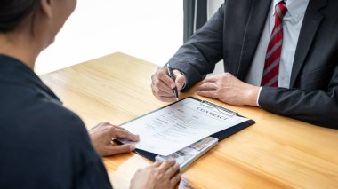 Rüşvet veren işadamına bir kalem veriyor ve iş adamına arazi ve gayrimenkul satın almada yolsuzluk yaparken sözleşme imzalaması için şartları sunuyor.