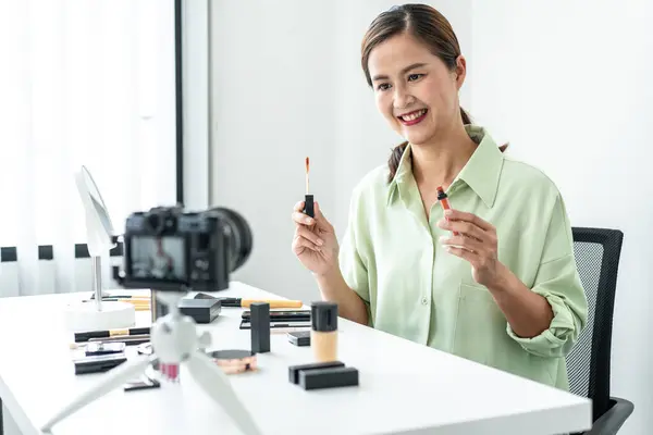 Woman blogger is present make up tutorial beauty cosmetic review product and broadcast live streaming video to teaching online on the camera screen at office studio.