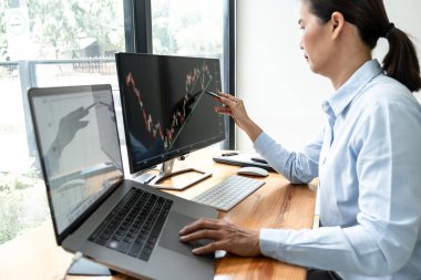 İş kadını yatırımcı, bir borsada sunulan verileri ekranda göstererek grafik verilerini planlayıp analiz ediyor..