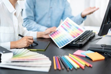 Yaratıcı grafik tasarımcı takımı, iş yerinde yeni bir koleksiyon oluşturmak için renk örnekleri çizelgesi üzerinde çalışıyor.