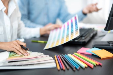 Yaratıcı grafik tasarımcı takımı, iş yerinde yeni bir koleksiyon oluşturmak için renk örnekleri çizelgesi üzerinde çalışıyor.