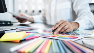 İş yerindeki grafik tabletinde renk seçimi ve çizim üzerine çalışan genç yaratıcı grafik tasarımcısı, yeni bir koleksiyon oluşturmak için ilhamda seçim renklendirmesi için renk örnekleri çizelgesi
