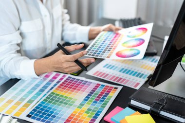 İş yerindeki grafik tabletinde renk seçimi ve çizim üzerine çalışan genç yaratıcı grafik tasarımcısı, yeni bir koleksiyon oluşturmak için ilhamda seçim renklendirmesi için renk örnekleri çizelgesi