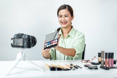 Kadın blogcu, makyaj malzemesi kozmetik inceleme ürünü ve canlı yayın videosunu kamera ekranında sosyal ağ öğretimine gösteriyor..
