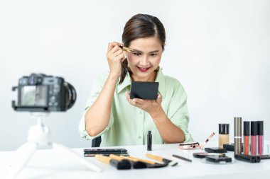 Kadın blogcu, makyaj malzemesi kozmetik inceleme ürünü ve canlı yayın videosunu ofis stüdyosundaki kamera ekranında öğretmenliğe sunuyor..