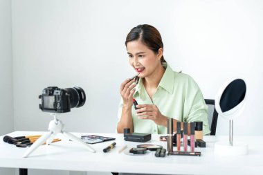 Kadın blogcu, makyaj malzemesi kozmetik inceleme ürünü ve canlı yayın videosunu ofis stüdyosundaki kamera ekranında öğretmenliğe sunuyor..