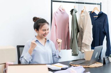 Moda tasarımcısı kadın tasarımcısı ürünleri satmak ve çevrimiçi sipariş almak için canlı yayın videosu yayınlıyor ve evdeki müşteriye teslimat için giysileri paketleyip kutulara koyuyor..