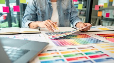 İş yerindeki grafik tabletinde renk seçimi ve çizim üzerine çalışan genç yaratıcı grafik tasarımcısı, yeni bir koleksiyon oluşturmak için ilhamda seçim renklendirmesi için renk örnekleri çizelgesi.