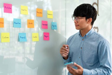 İş adamı yöneticisi düşünme ve yeni bir pazarlama projesinin planlanmasında kullanılacak anahtar kelimeyi not alıyor..