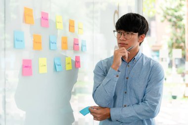 İş adamı yöneticisi düşünme ve yeni bir pazarlama projesinin planlanmasında kullanılacak anahtar kelimeyi not alıyor..