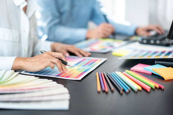 Team of creative graphic designer working on color swatch samples chart for selection coloring in inspiration to create new collection at workplace
