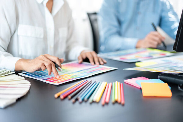 Two creative graphic designer team working on color selection and drawing on graphic tablet, Color swatch samples chart for selection coloring in inspiration to creativity at workplace.