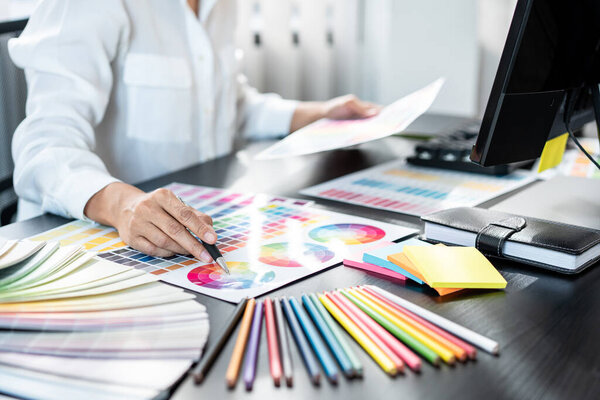 Young creative graphic designer working on color selection and drawing on graphics tablet at workplace, Color swatch samples chart for selection coloring in inspiration to create new collection