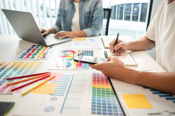 Две творческие команды графических дизайнеров, работающие над выбором цвета и рисованием на графическом планшете, график образцов цветовых образцов для выбора раскраски в духе творчества на рабочем месте.