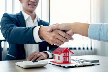 Emlakçı ve müşteriler, ev sigortası ve yatırım kredisi imzaladıktan sonra bitirilen sözleşmeyi kutlamak için el sıkışıyor.