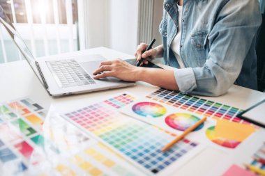 İş yerindeki grafik tabletinde renk seçimi ve çizim üzerine çalışan genç yaratıcı grafik tasarımcısı, yeni bir koleksiyon oluşturmak için ilhamda seçim renklendirmesi için renk örnekleri çizelgesi.