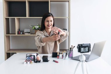 Mutlu gülümseyen zarif kadın ya da video kaydında fırçasıyla güzellik blogcusu. İnceleme ürünü kamera ekranında video blogları hakkında özel ders hazırlıyor..